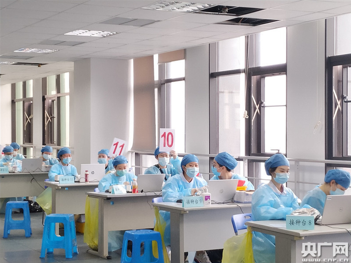新冠疫苗接种区志愿者举起号码牌，方便市民找到空的接种台进行接种（央广网记者林馥榆 摄）