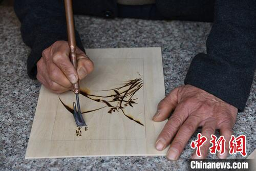严绍明在创作黄岩火烙画《兰》 范宇斌 摄