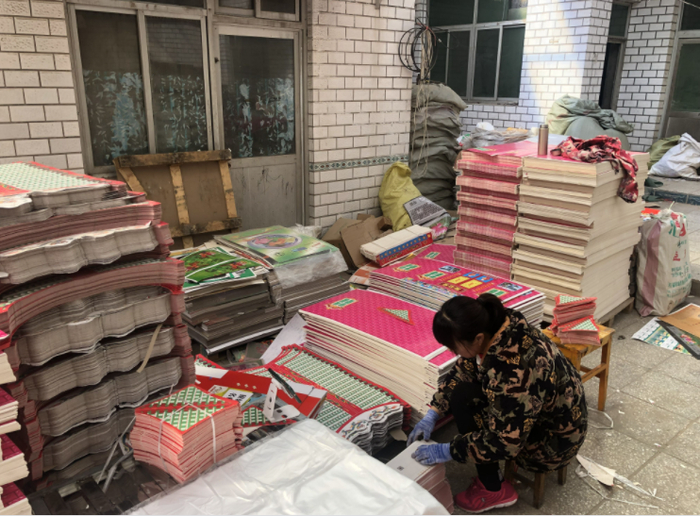 一名女工坐在小板凳上分装祭祀用的三层楼“别墅”。新京报记者 张静姝 摄