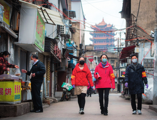 ▲ 2020年2月7日，武汉市中华路街西城壕社区党委书记翁文静（右二）与志愿者柳莹（右三）、张琦（右一）上街进行防疫宣讲 肖艺九摄/本刊