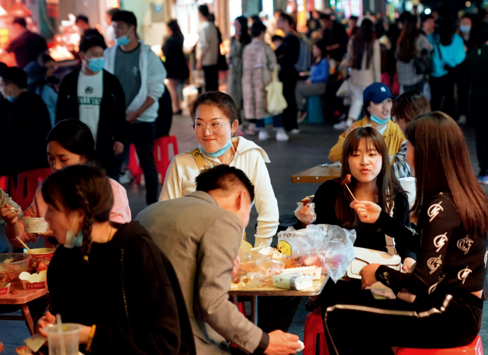 ▲ 年轻人在武汉著名的户部巷品尝小吃（3月28日摄） 程敏摄/本刊