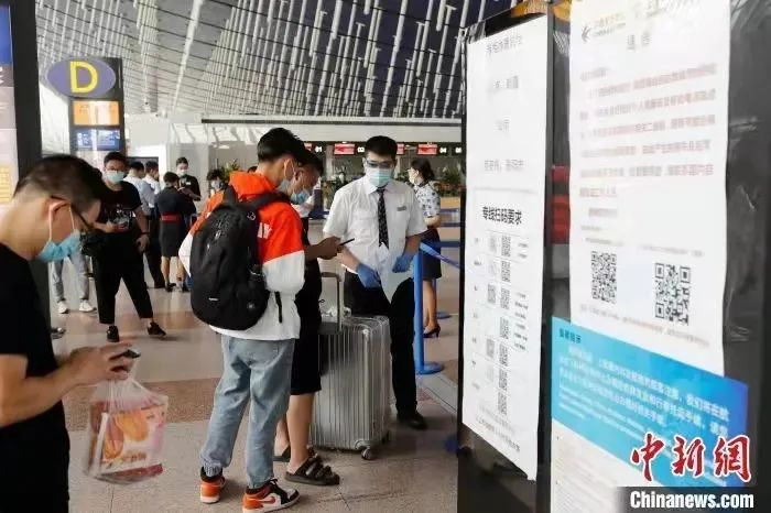 旅客在工作人员的帮助下扫码办理登机手续。图源：中新网
