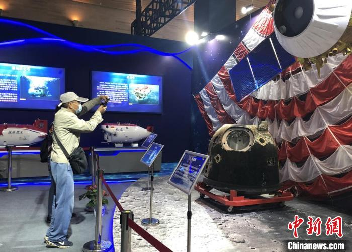 市民拿出手机拍摄成果展中展出的实物及模型。　孙权 摄