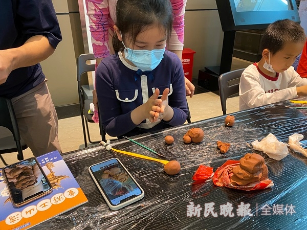 图说：小朋友学习雕塑陶泥狮子