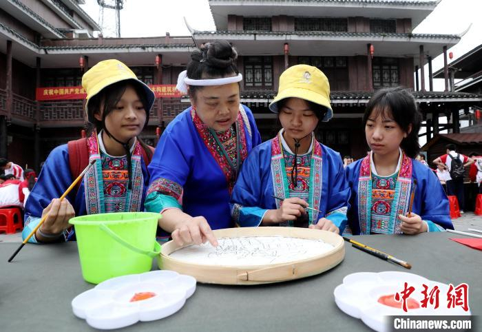 侗族画家杨梅香在指导学生绘侗族簸箕画。　吴练勋 摄