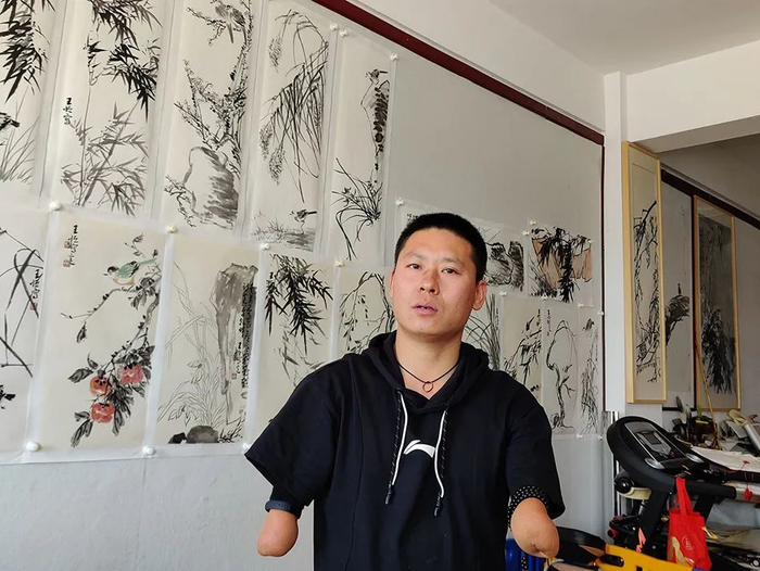 王恒讲诉自己的考研历程，身后是他的画作（图源：澎湃新闻）
