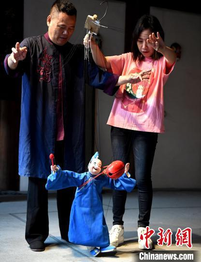 现场一名女性观众上台体验泉州提线木偶戏的表演技艺。　记者 刘可耕 摄