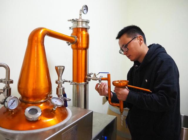 郭江正在调试酿酒的蒸馏设备。新华社记者 金一清 摄