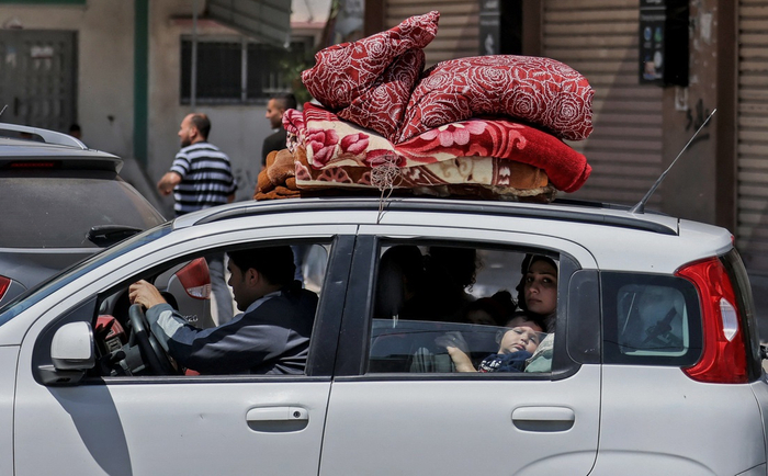 当地时间5月14日，在加沙地带北部的拜特哈农，巴勒斯坦一家人携带着简单的生活用品准备去往安全地点。