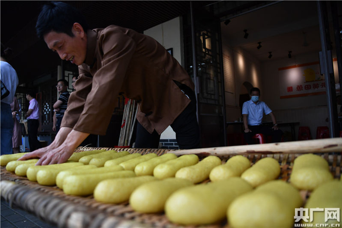 将趁热的黄元米果搓成条状进行晾晒（央广网记者 胡斐 摄）