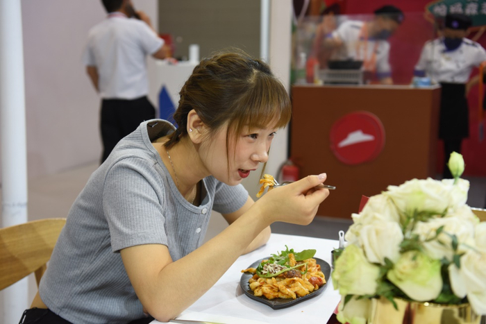 消费者在中博会必胜客展区品尝西冷牛排帕马森芝士刀削面