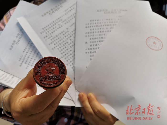 西引力小区原业委会成员展示其保管的公章及胜诉判决。