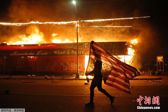 　　2020年5月28日，美国明尼阿波利斯，抗议者在街头举着美国国旗，当时他正在为乔治·弗洛伊德遭暴力执法致死抗议。Julio Cortez