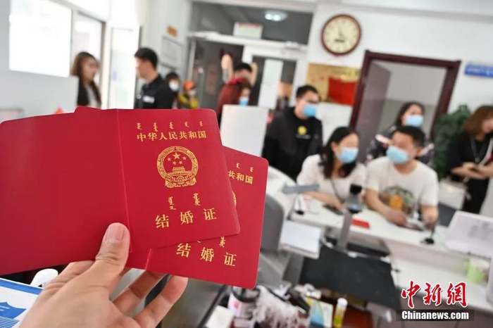 资料图：5月20日，内蒙古呼和浩特市，新人们排队办理结婚证。中新社记者 刘文华 摄