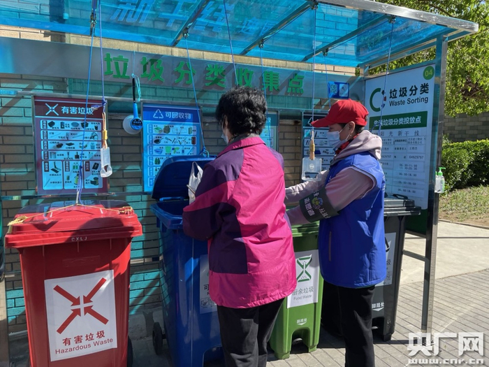 北京朝阳区大屯街道，垃圾桶盖可以通过拉绳另一端的把手开启，并用把手上的挂钩固定在开启位置，方便双手操作破袋投放厨余垃圾（总台央广记者 白杰戈 摄）