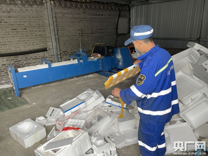 工作人员撕除泡沫包装箱上的胶带，准备投入冷压机处理（总台央广记者 白杰戈 摄）