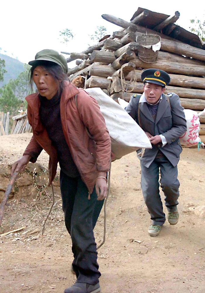 这是2005年1月11日，妻子韩萨帮助王顺友从邮局背回沉重的邮件包裹。 新华社 记者 陈凯 摄