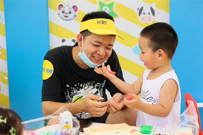宝宝向爸爸“炫耀”自己刚捏出的太空胡萝卜。齐齐哈尔市委宣传部 供图