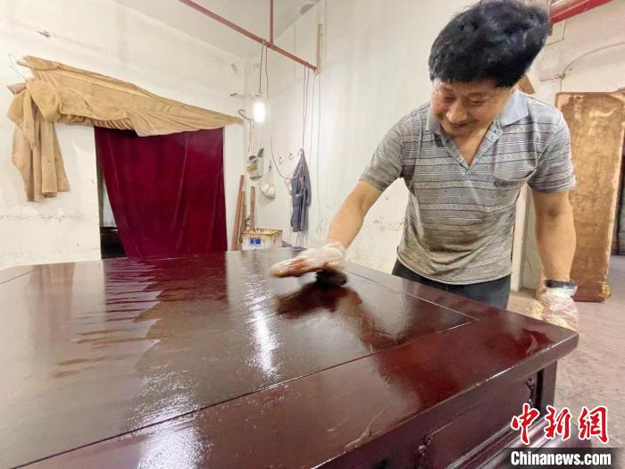 花园村某红木家具企业，工人给红木家具上漆，使其寿命更长久。　张斌 摄