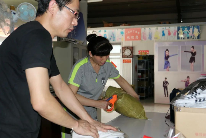 ▲徐伟和妻子赵金平在打包货物，背后的墙上贴着“梦想多大，就能飞多高”的牌子。