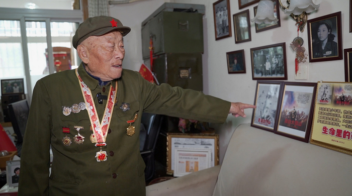 ▲张文辉老人为记者介绍其参加百团大战、黄崖洞保卫战等著名战役的老照片