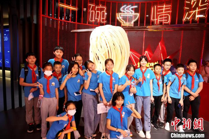 研学学生在螺蛳粉模型前合影。　朱柳融 摄