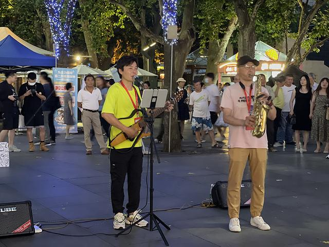 杜烁辰（左）在静安公园门口演唱。澎湃新闻记者 陈伊萍 摄