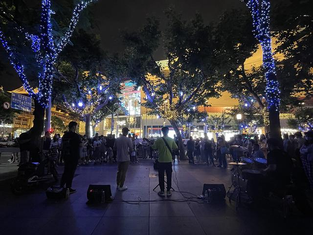 夜色下的静安公园门口街头艺人表演，吸引了市民驻足观看。澎湃新闻记者 陈伊萍 摄