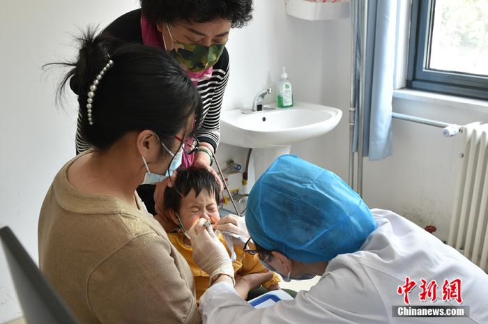 郑宝英正在为患儿看诊 中新网记者 翟璐 摄