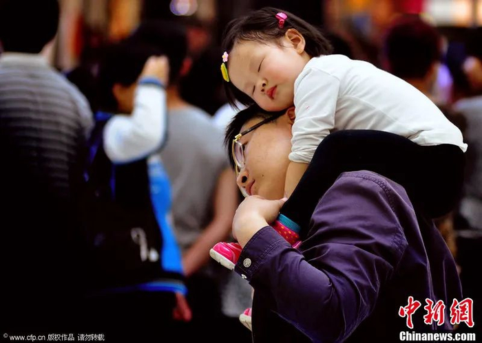 女童坐在父亲的肩上酣然入睡。邓寅明 摄