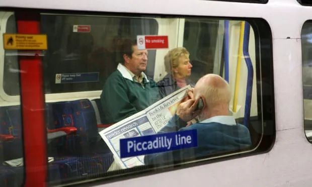 乘客在地铁上看报纸 图片来源：卫报