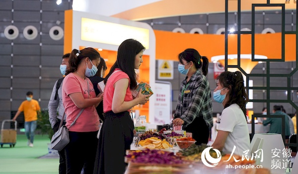 　　顾客在亳州馆展台购买花草茶。人民网 王锐摄