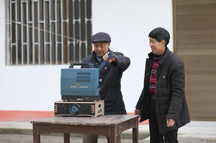 谢玉年给乐正洪演示老式电影放映机的操作流程（央广网发 赵军摄）