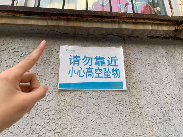 （小区内挂着许多“小心高空坠物”的提示牌。）
