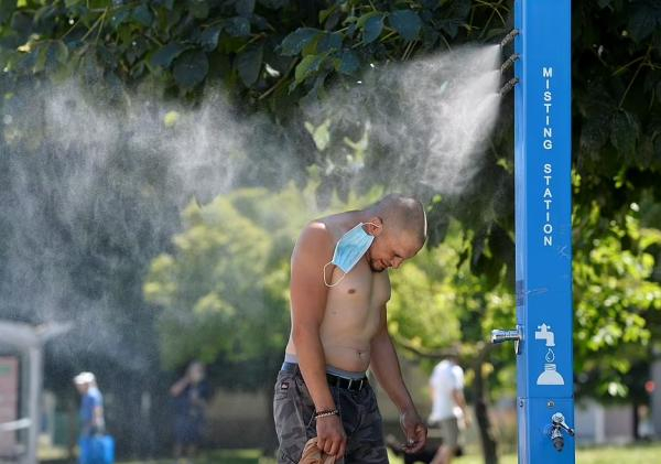 温哥华一男子在“喷雾站（misting station）”冲凉 图源：路透社 