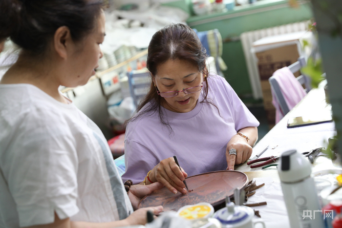 阎坤正在和同事沟通掐丝工艺细节（央广网记者 韩靖 摄）