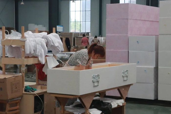 ▲5月24日，曹县一家棺材制造厂，工人们正在加工布棺。新京报记者 吴采倩 摄