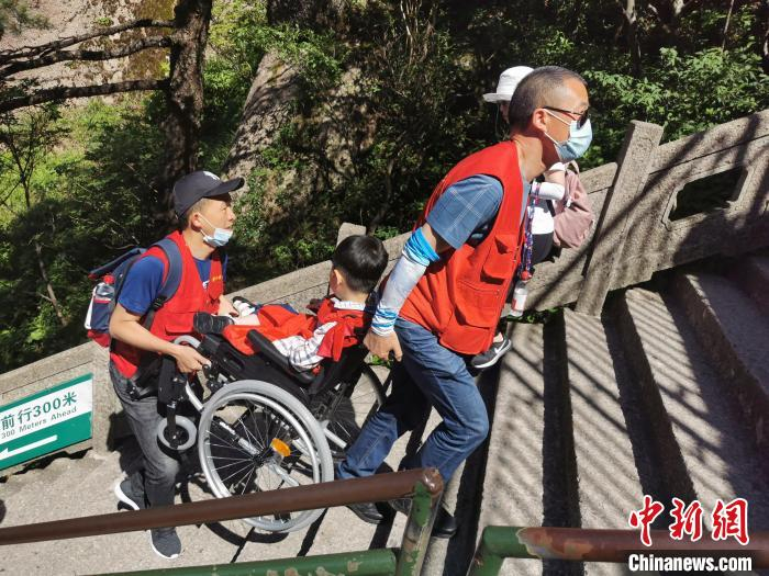 志愿者将罕见病儿童抬上山。　喻黎曙 摄