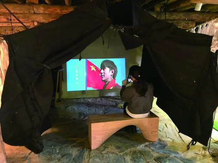 ▲5月27日，来自重庆的旅客王雪在博物馆里看丁真的宣传片。新京报记者 韩沁珂&nbsp;摄