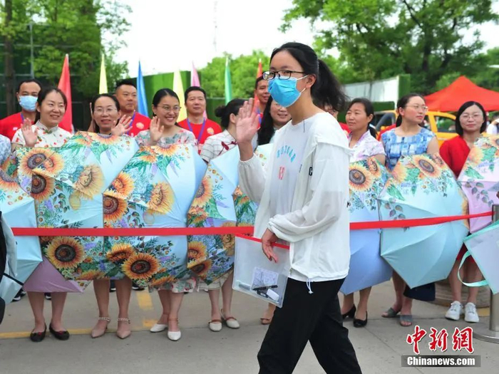 考生家长和老师身穿旗袍撑开带有向日葵图案的太阳伞为考生加油、鼓劲。中新社发 洪星 摄 图片来源：CNSPHOTO