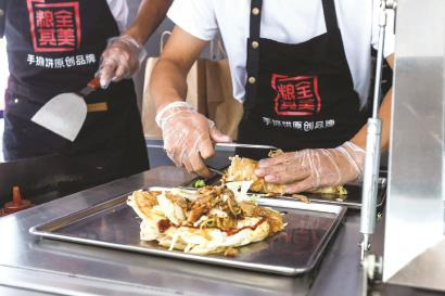 　　下图：流动餐车上，工作人员正在制作早餐。 记者 张伊辰 摄