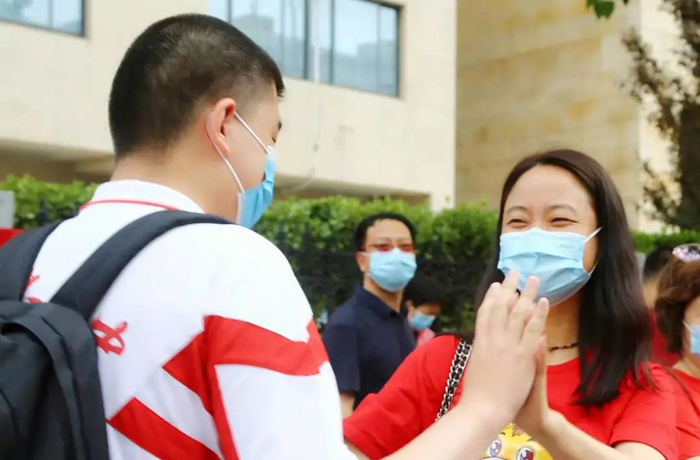 ▲北京高考第一天，刘翰文在考场外和政治老师击掌加油。受访者供图