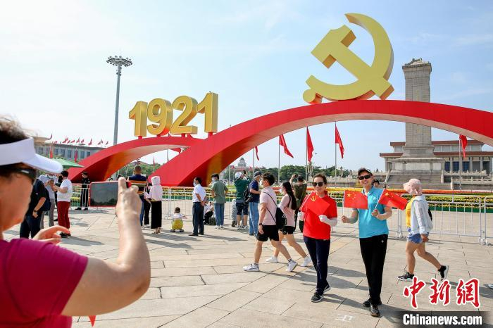 游客纷纷在党徽年号花坛前留影。　何建勇 摄