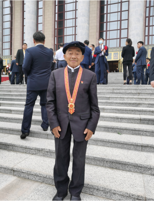 6月29日，在人民大会堂的台阶上，黄大发戴着“七一勋章”拍照留念。受访者供图 