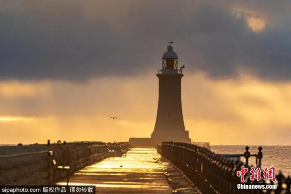 资料图：当地时间2021年3月5日，英国泰恩茅斯，海滨码头的日出，给海面铺上了一层金。图片来源：SIPAPHOTO