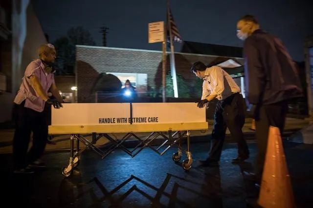 资料图片：在美国纽约昆斯区，殡仪馆工作人员准备将装有遗体的纸箱装车，运到外地处理。新华社发（郭克 摄）