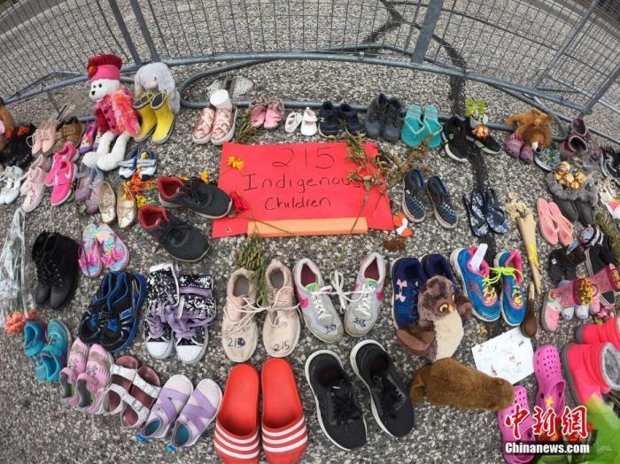 当地时间6月2日，在位于多伦多的加拿大安大略省省议会大楼门前，人们摆放了上百双童鞋和各式玩偶、鲜花、留言卡等，为该国一处原住民寄宿学校旧址发现215具儿童遗骸之事志哀。 中新社记者 余瑞冬 摄