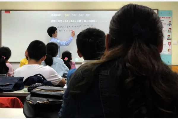 南京一家全国连锁培训机构的教学点内，一名培训人员为听课的学生辅导小学数学题。（新华社记者韩瑜庆摄）