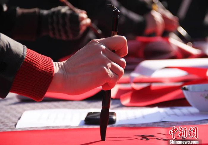 2014年1月，江西省乐平市花坛广场，书法家正在书写春联。中新社发 徐铮 摄