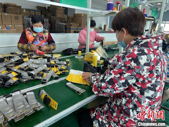 台企工厂内，工人们赶制棒垒球皮带 项菁 摄